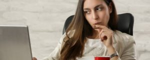 Young beautiful woman enjoying a piece of chocolate at the office table during a coffee break